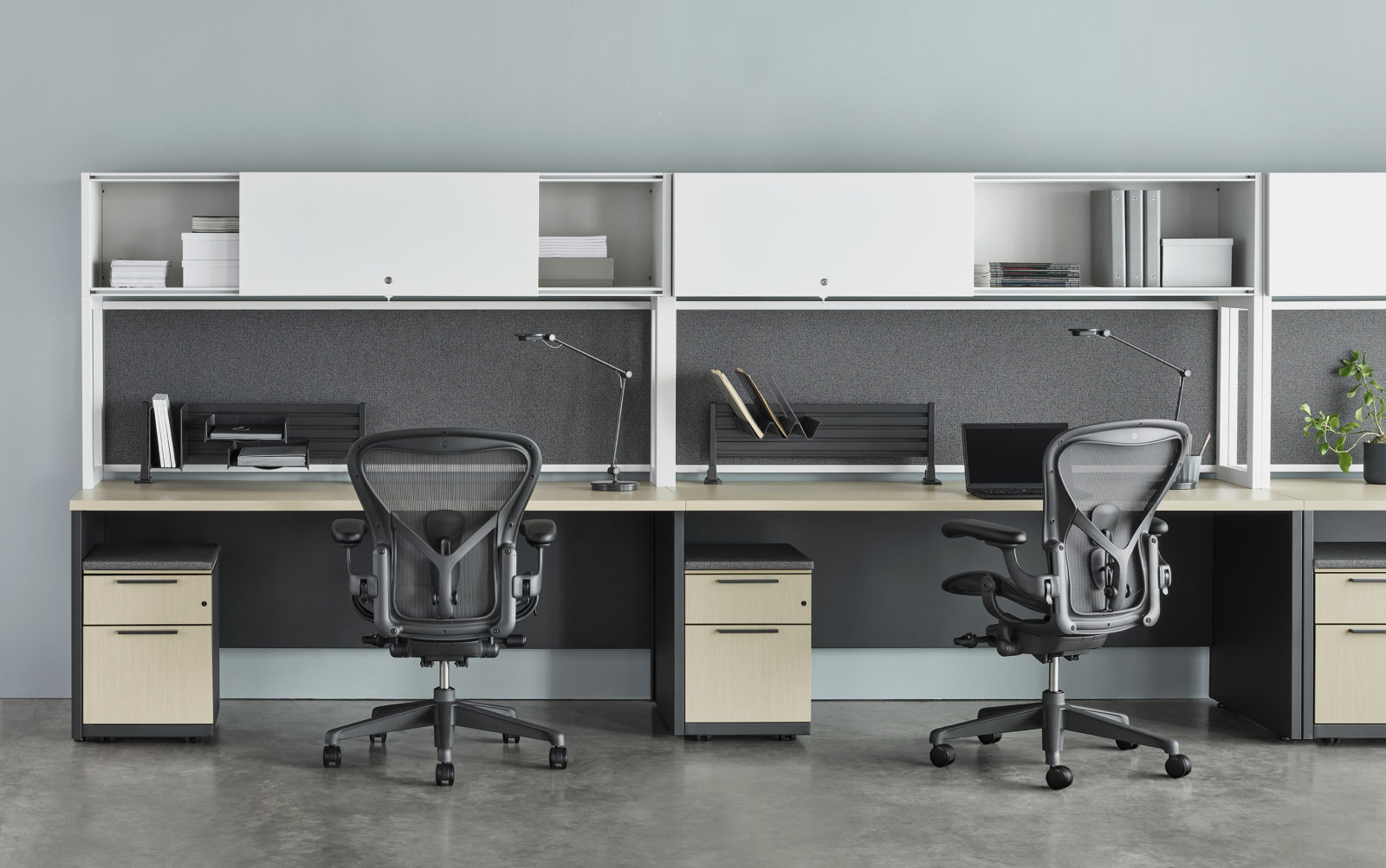 Straight run of Herman Miller workstations with white overhead storage, Aeron chairs and mobile pedestals