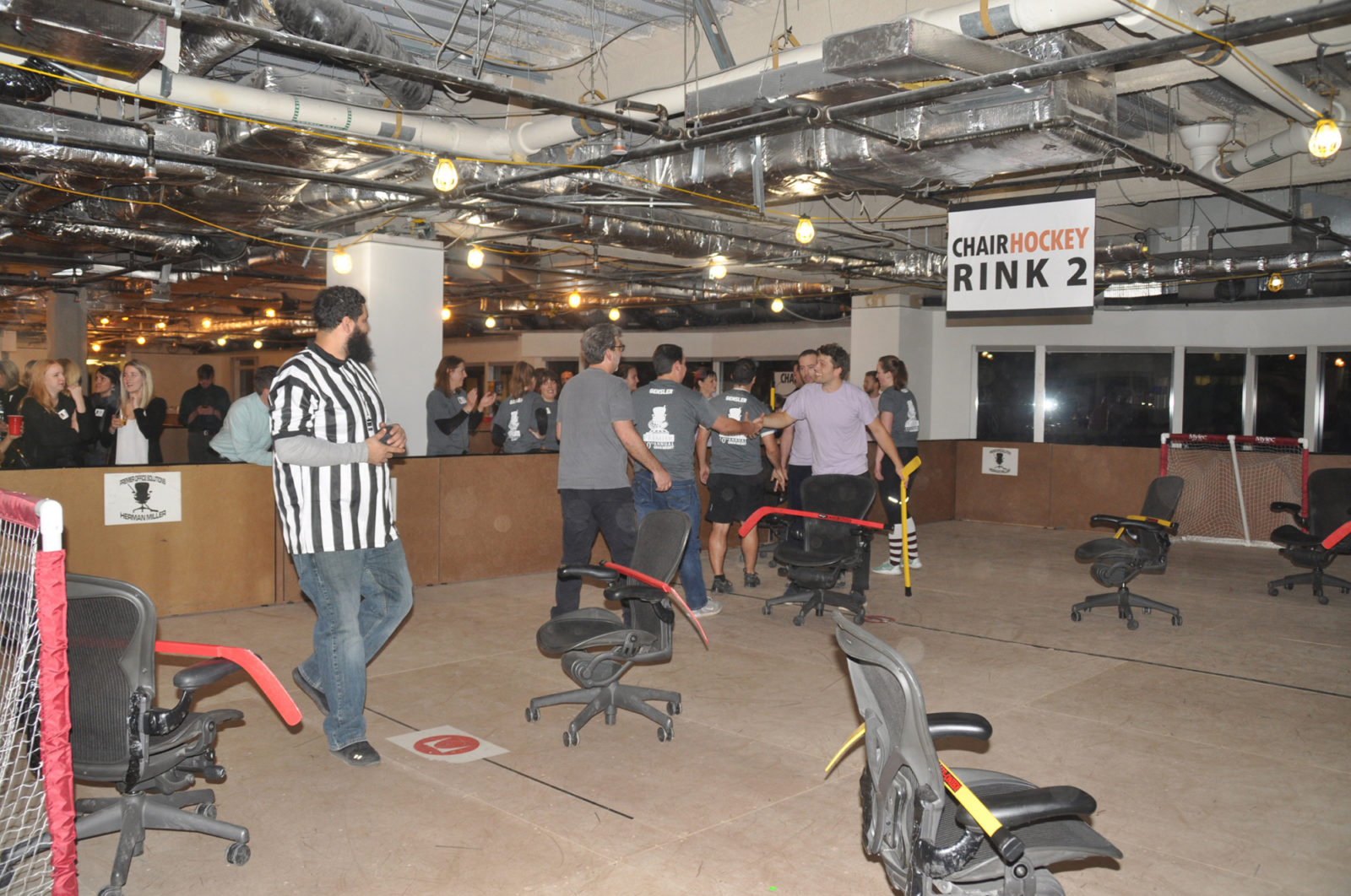 Indoor hockey rink with players shaking hands after match. They just finished a game of chair hockey, playing hockey in Herman Miller Aeron chairs.