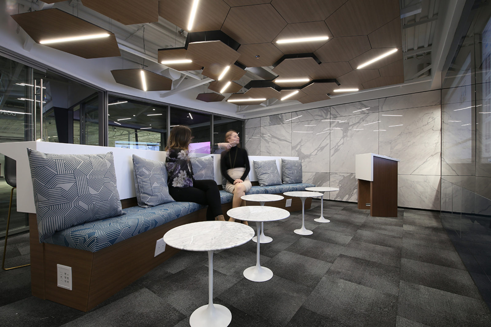 Collaborative space inside DIRTT room, 2 women sitting on booth seating, DIRTT ceilings and walls