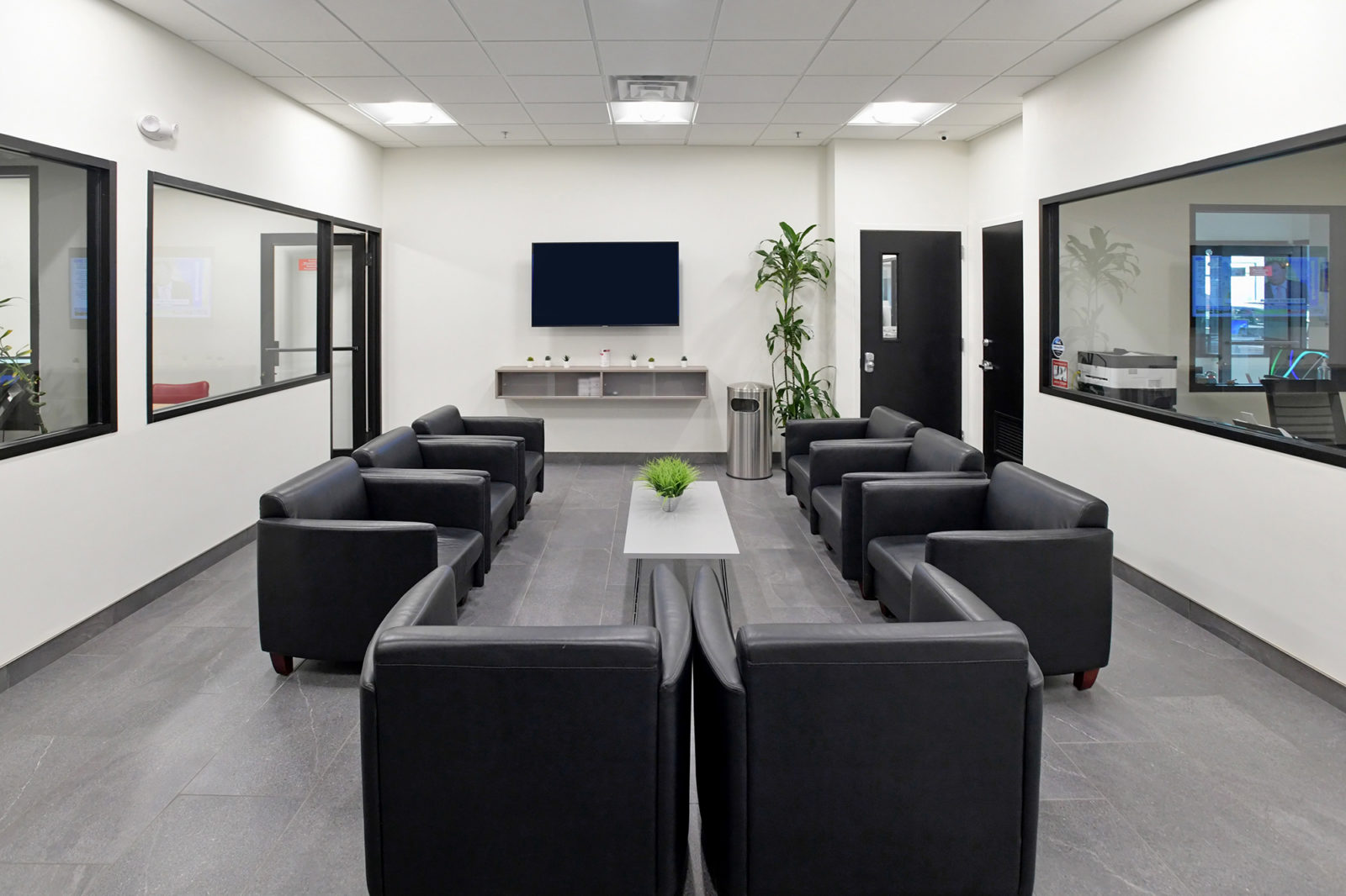 Waiting area with individual black leather club chairs creating a U-shape area.