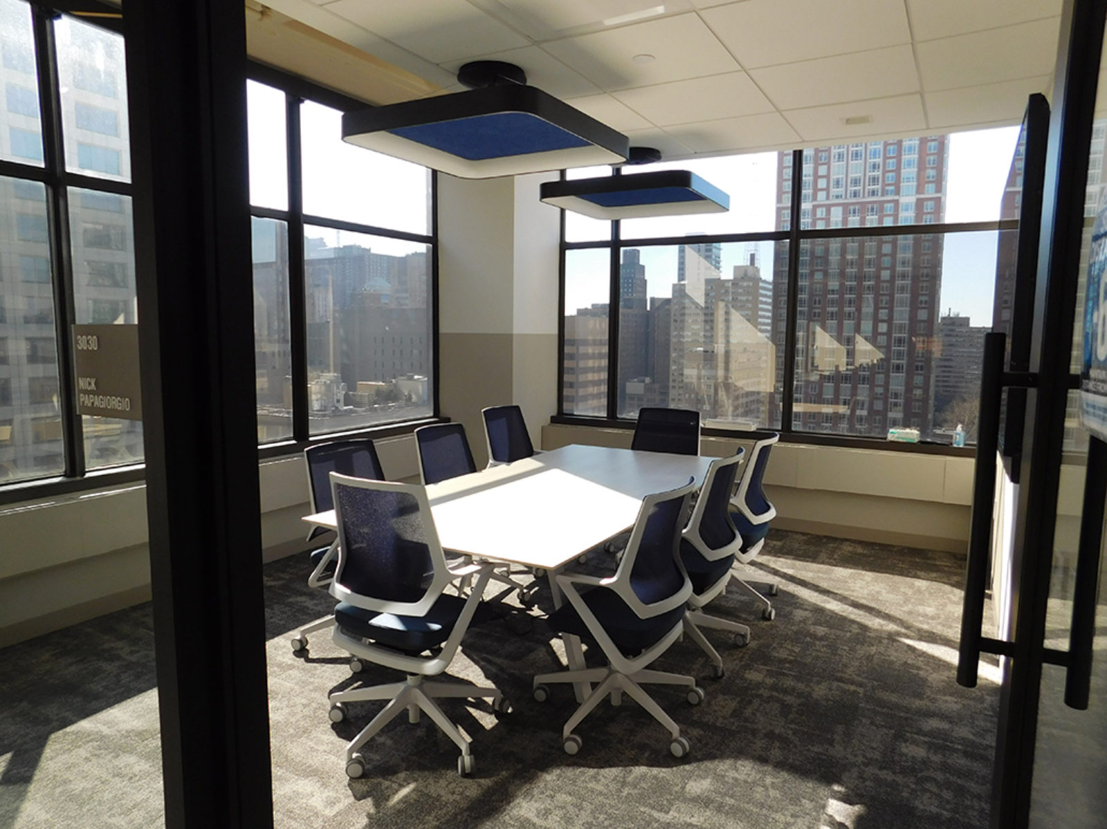 Corner meeting room with a lot of windows, conference table with dark blue mesh chairs around table
