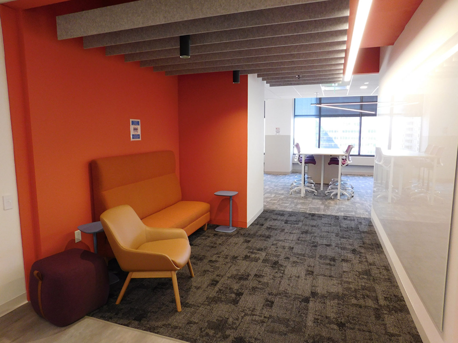 Orange wall with orange banquette seating, one mustard color lounge chair