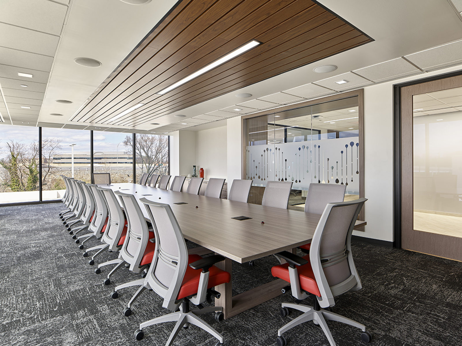 Conference room with wooden table, chairs with red fabric seat and grey mesh back