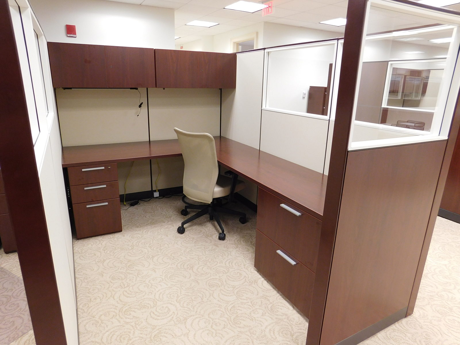L-shape workstation with dark wood worksurfaces and storage, light fabric panels inside, cream color task chair