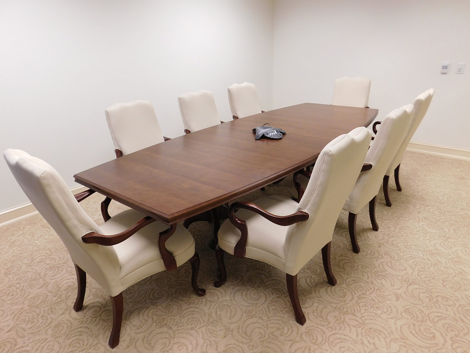 Dark woodgrain conference table with 8 white armchairs