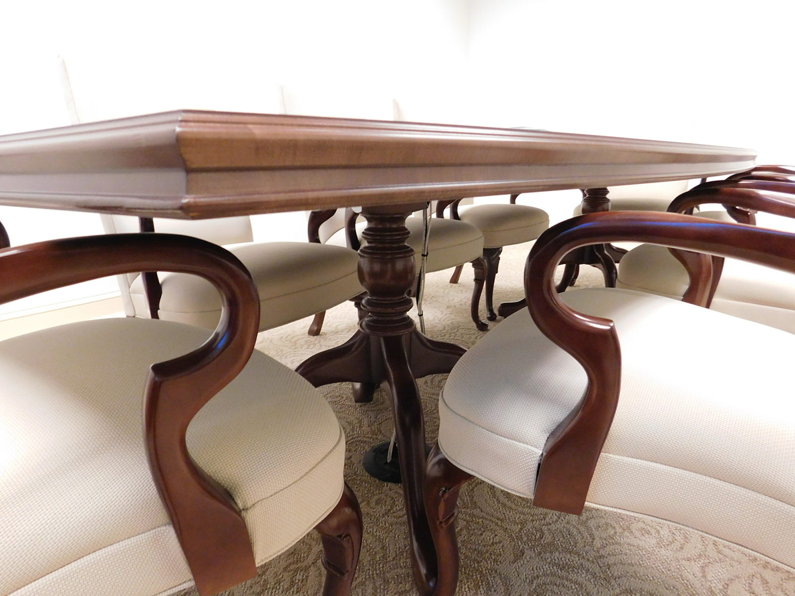 Detail shot of bevel edge of conference table and curved shape of wooden arms on chairs