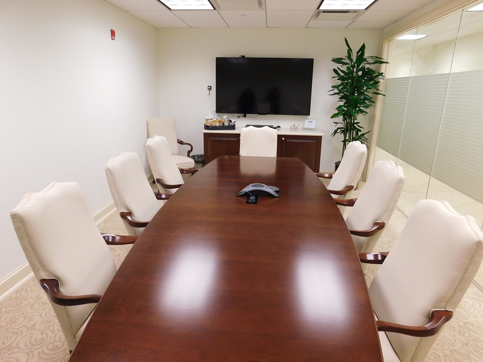 Dark wood, boat-shaped conference table with traditional white leather chairs