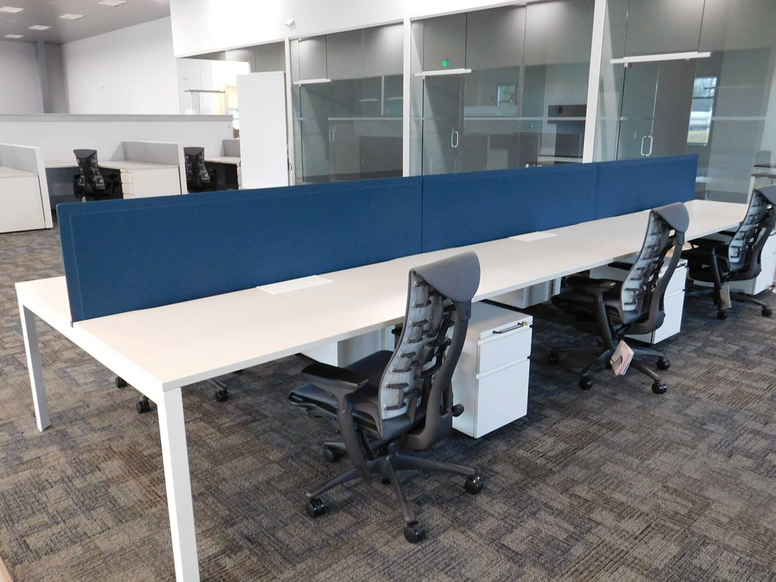 Herman Miller benching stations with blue fabric screen down center, grey Embody chairs