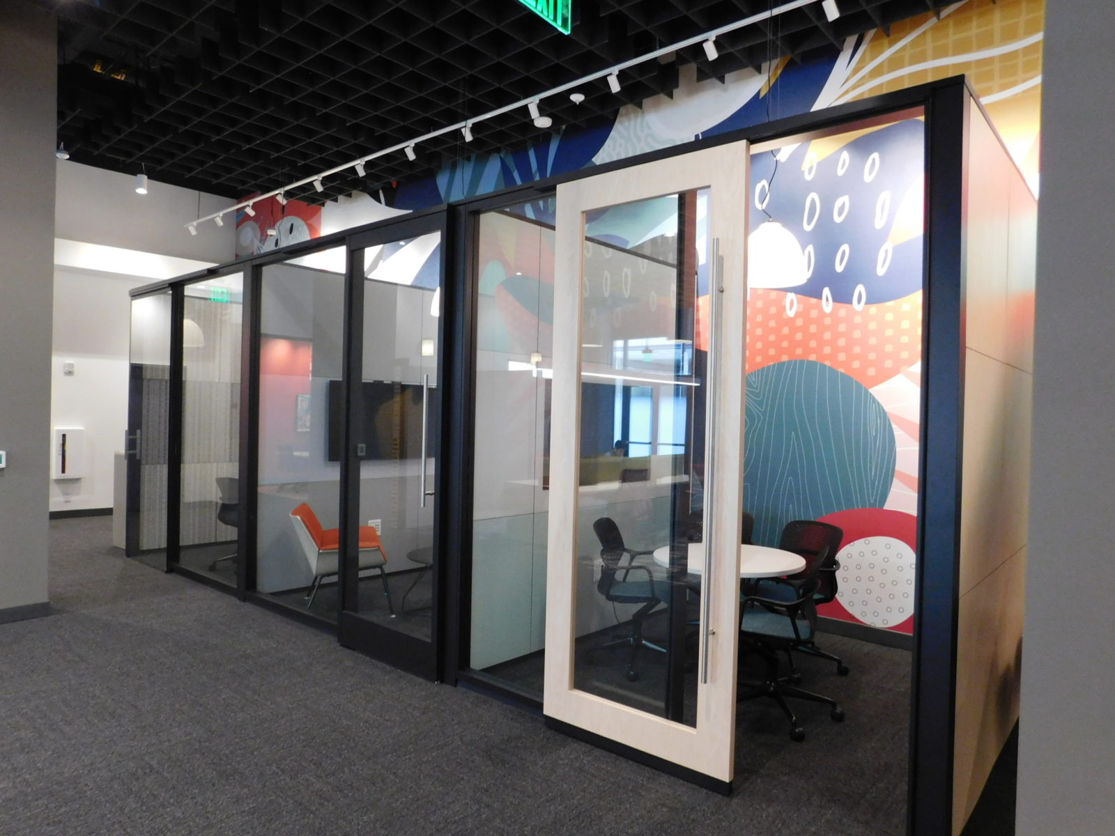 View of an entire row of DIRTT modular solution. 3 rooms of glass walls and doors with different collaborative settings in each room.