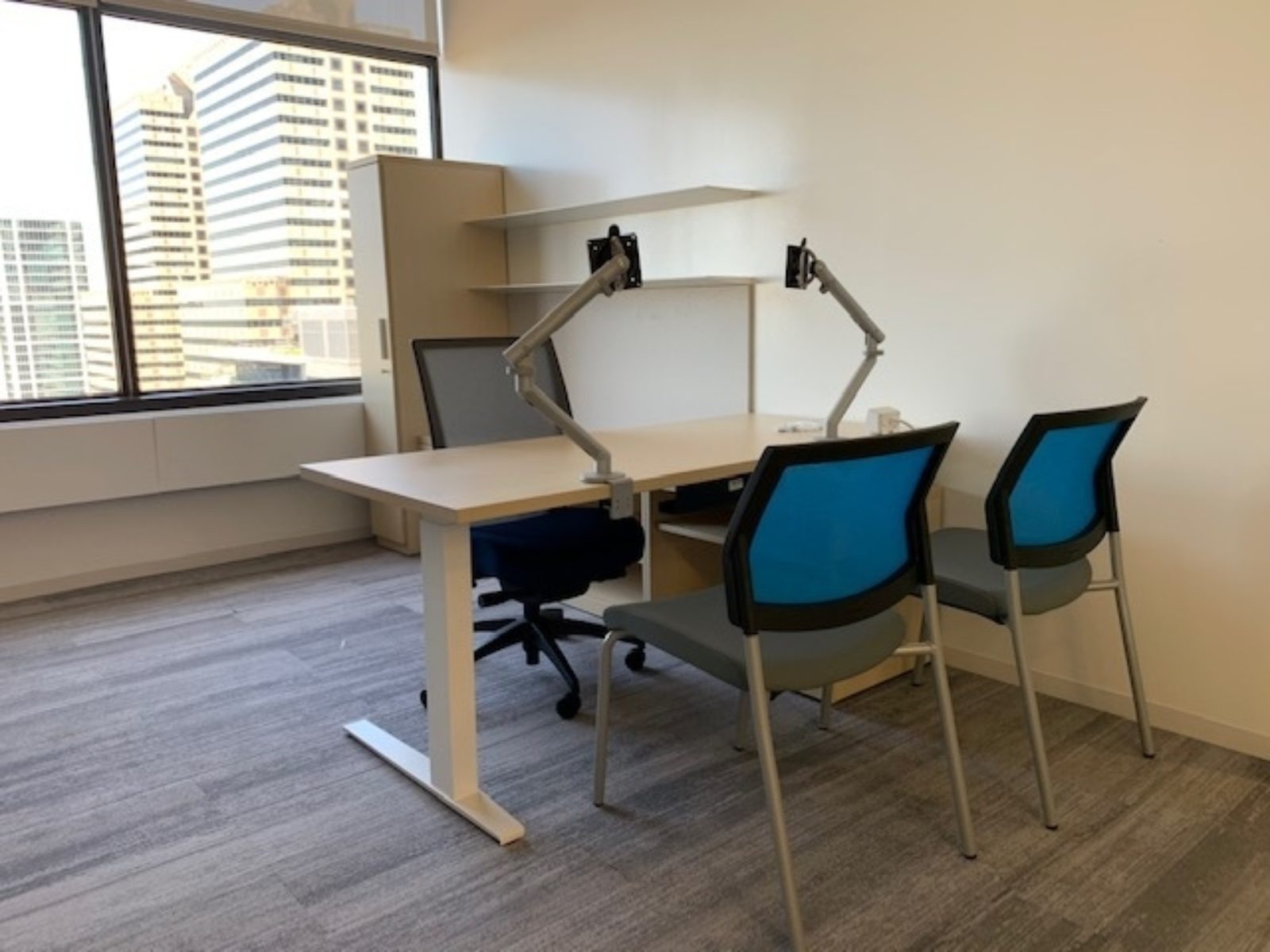 Herman Miller private office with height-adjustable desk, open shelves and storage unit. Desk has one task chair and two guest chairs.