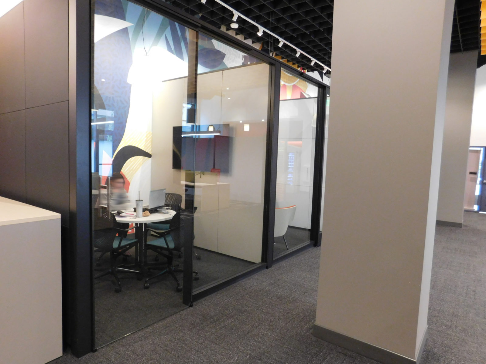 DIRTT modular wall solution: they have glass doors and wall on front with black trim; the rooms are separated by a fabric wall in between.