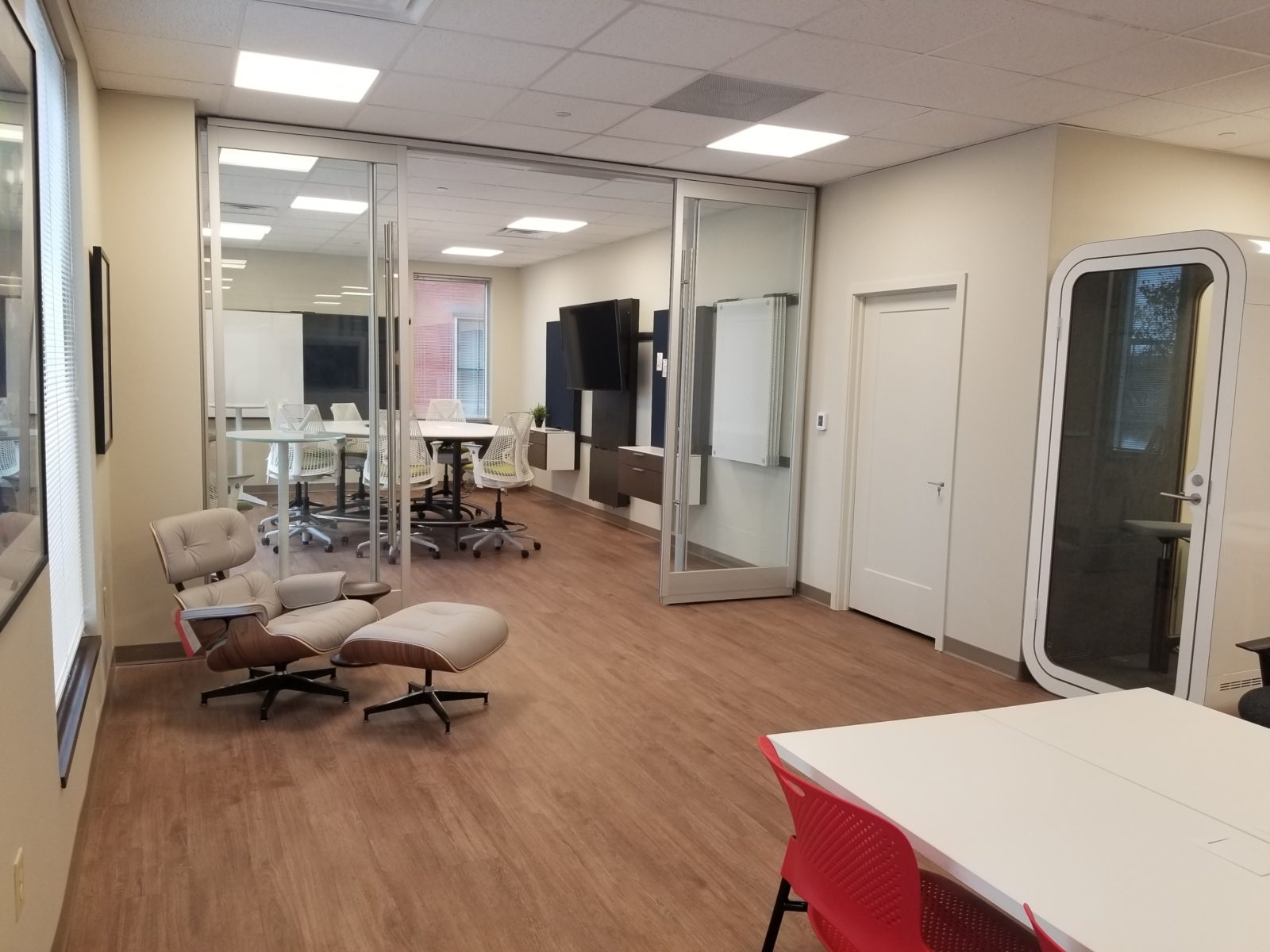 View of back conference room with DIRTT glass walls; Herman Miller Eames Lounge on left; Framery single pod on right; Herman Miller Exclave in back.