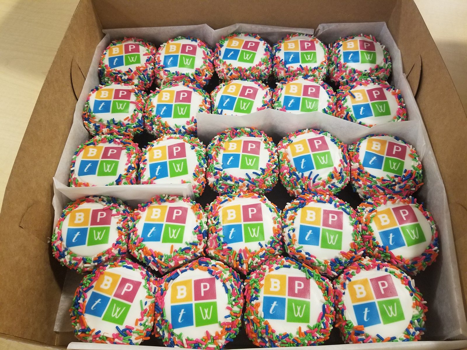 Custom cupcakes with the Best Places to Work logo (BPTW) and colorful sprinkles on edges of cupcakes.