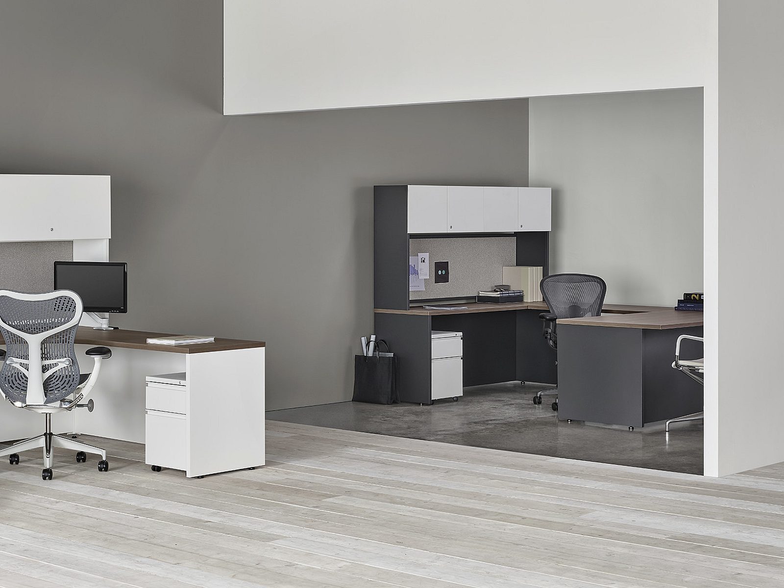 Cluster of 2 Herman Miller workstations in white finish with dark wood tops; U-shape private office in background in black finish with dark wood tops