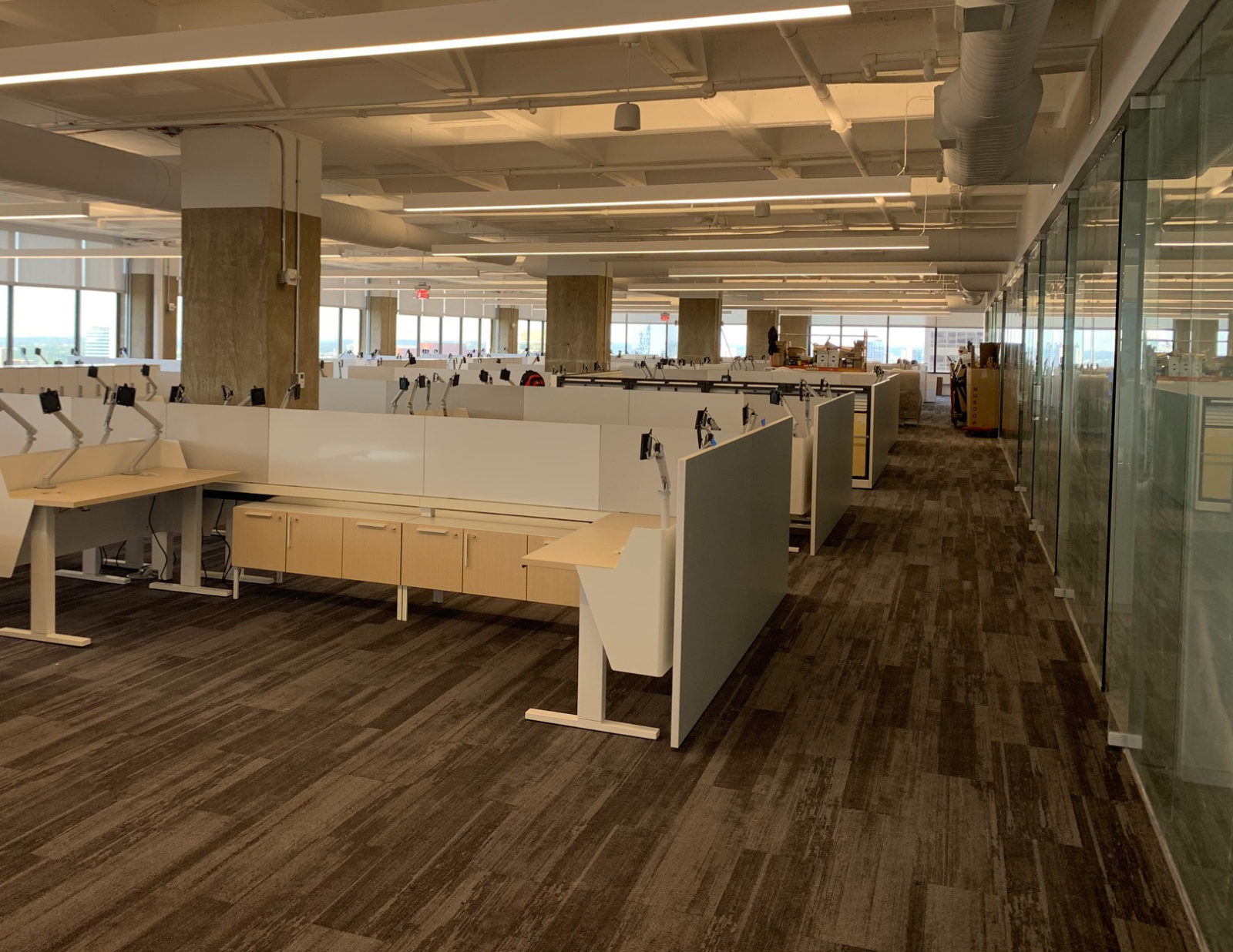 Open area with Herman Miller Vista height-adjustable workstations. Stations are oak laminate with white metal trim and modesty panels