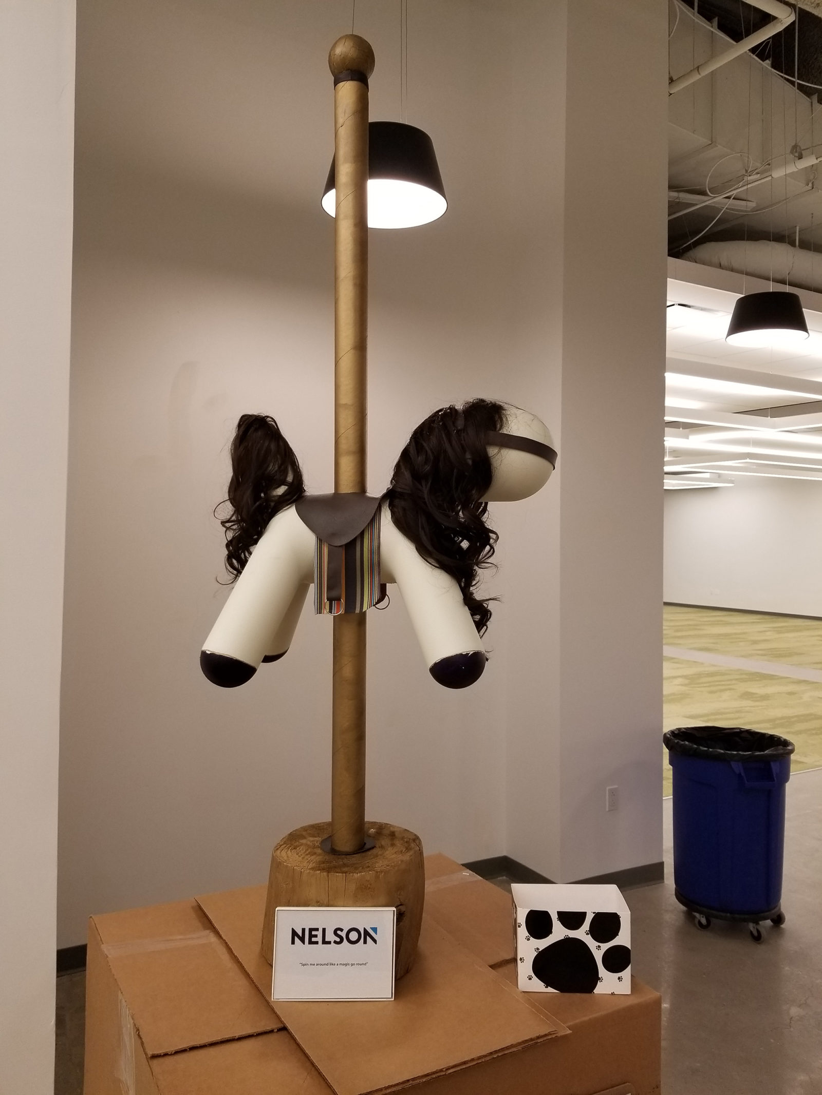 White dog statue with a mane and tail attached to make it look like a horse. There is also a pole that goes through it like a merry-go-round.