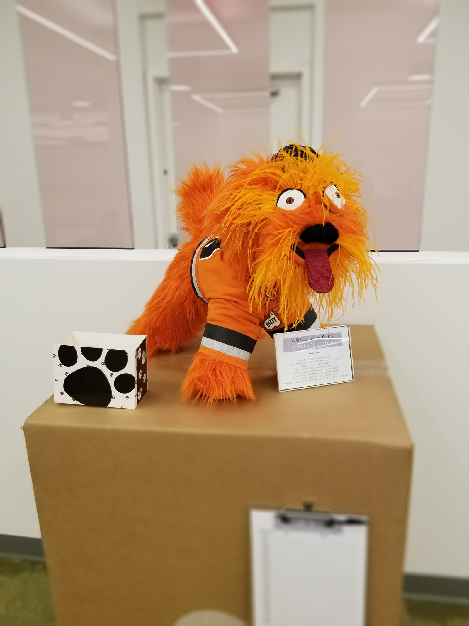 Dog statue decorated to look like Gritty, the Philadelphia Flyer's mascot. Bright orange fur with big, crazy eyes, wearing a Flyers jersey.